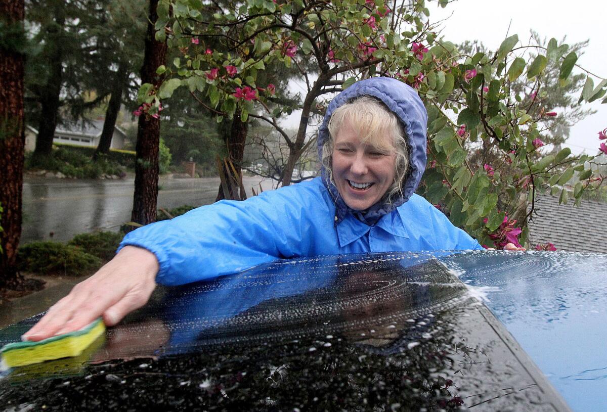 In this 2014 file photo, Jacqueline Davolio takes advantage of the rain to wash her car in a downpour rather than to otherwise use municipal water during the long drought.
