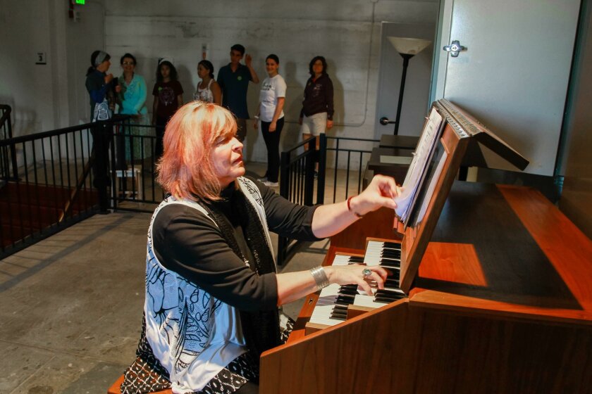 Gina Seashore plays the carillon inside the California Tower in Balboa Park as members of a tower tour look on. The carillon makes the bell-like sounds that ring throughout the park.