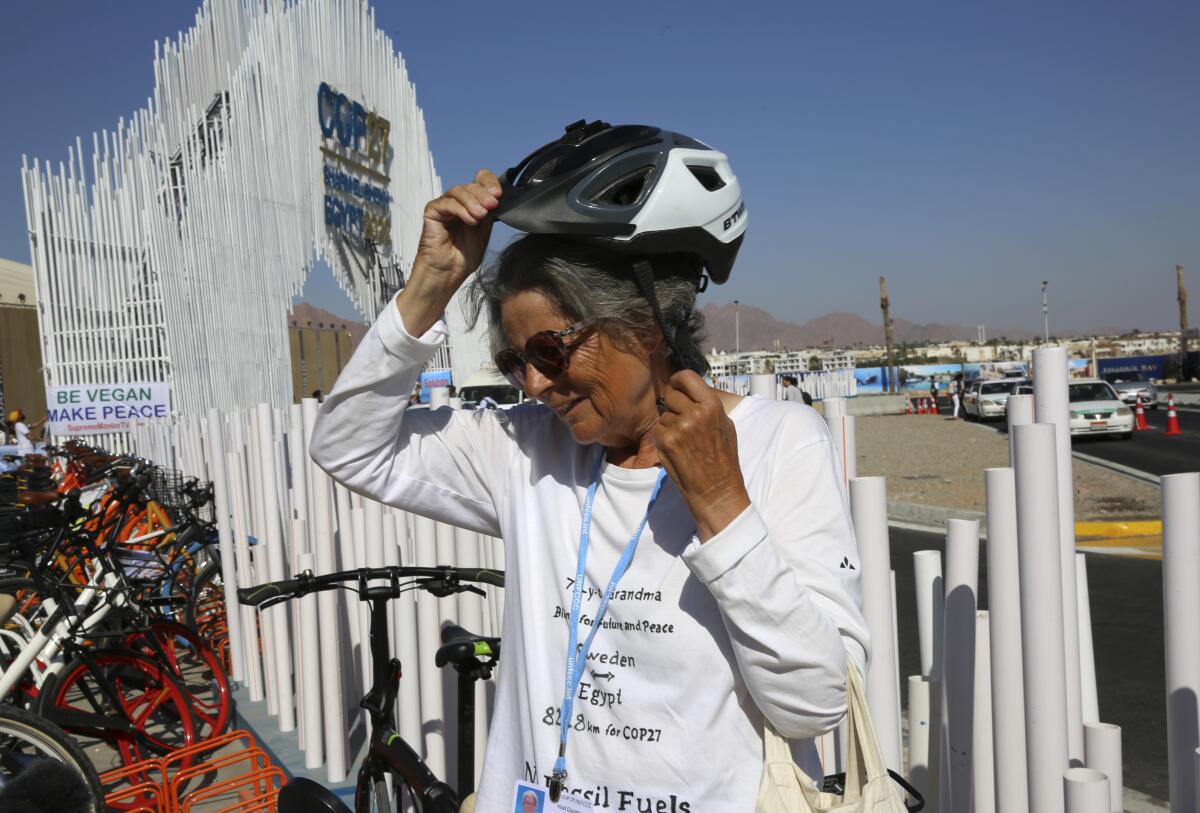 Dorothee Hildebrandt, 72, removes her bike helmet after arriving to the U.N. climate summit COP27 venue in Sharm el-Sheikh, Egypt, Saturday, Nov. 12, 2022. Hildebrandt biked from Sweden to Sharm el-Sheikh, Egypt, for COP27 to raise awareness and urge world leaders gathered at the conference to take concrete steps to stop climate change. (AP Photo/Thomas Hartwell)
