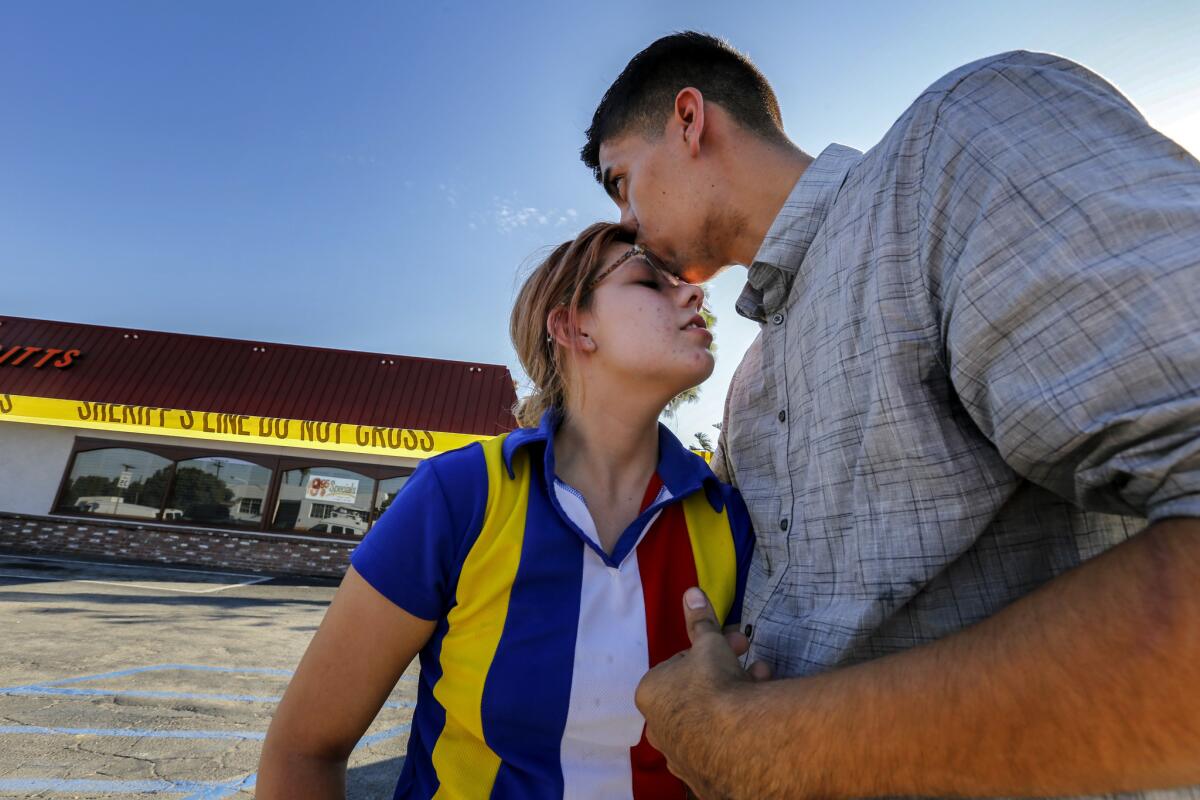 High school sweethearts, Madelynn Bastidas, left, and Oscar Madriles, hug each other in front a Downey barbecue restaurant where they were dining when a gunman ran in and took hostages.
