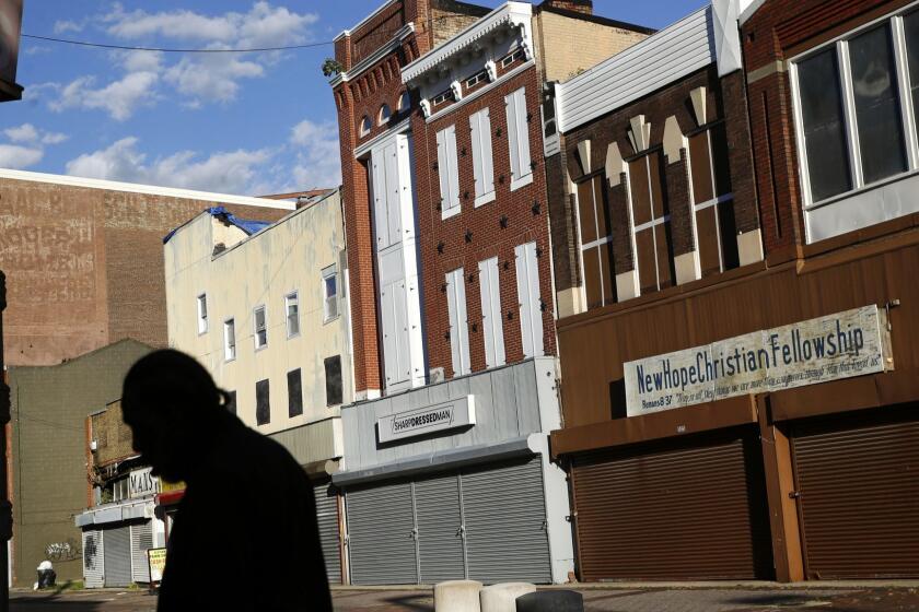 In this Tuesday, Oct. 17, 2018 photo, a man walks past vacant storefronts at the Old Town Mall in Baltimore. Job growth was supposed to be a cure-all to stop the wealth gap from worsening, but new research suggests that impoverished Americans are getting left out even when their communities enjoy hiring booms. (AP Photo/Patrick Semansky)