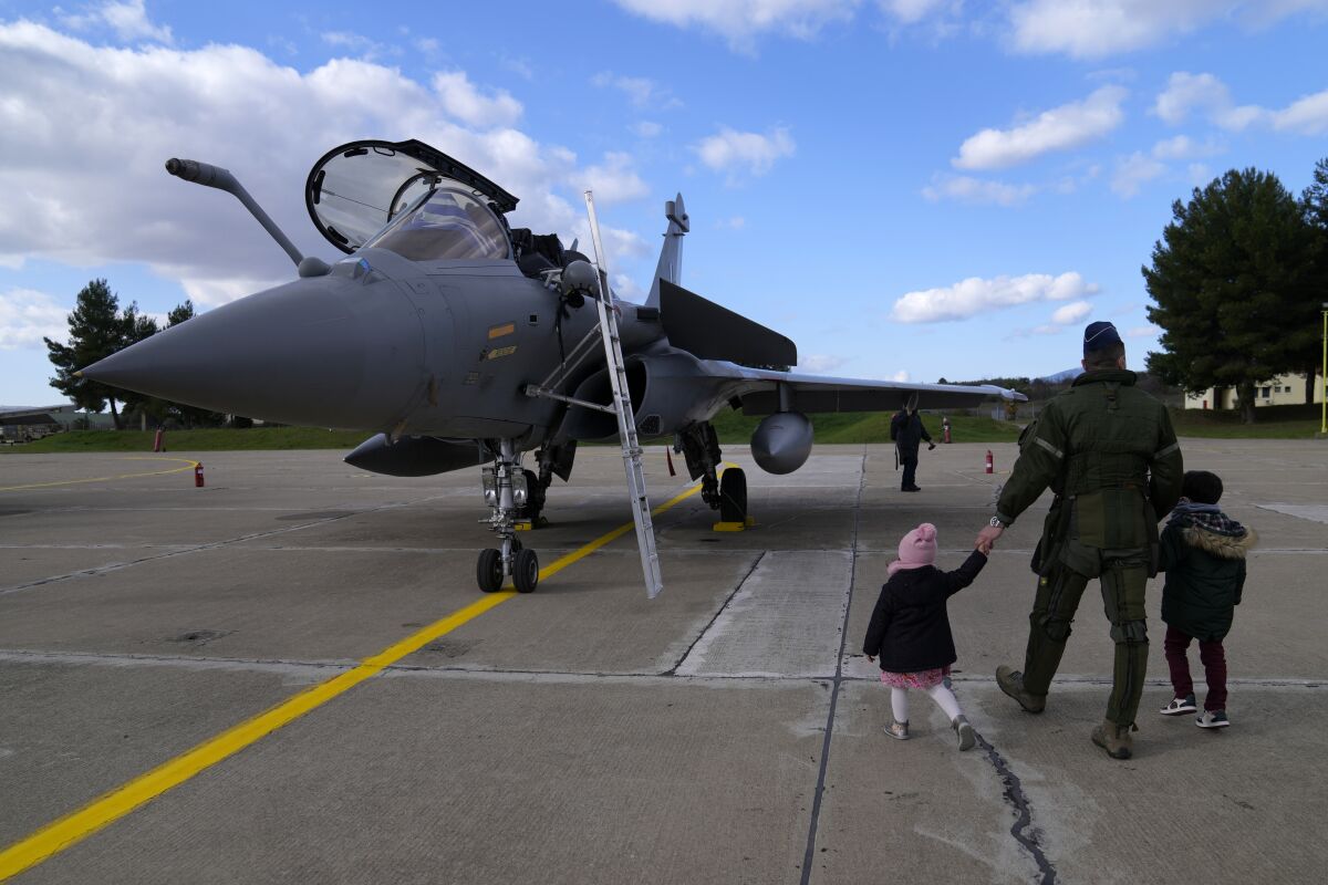 Flying Officer Panagiotis Tsoumanis, pilot of the Rafale fighter jet, shows to his kids Ioanna, left, and Thomas the aircraft during a handover ceremony in Tanagra military air base, about 82 kilometres (51miles) north of Athens, Greece, on Wednesday, Jan. 19, 2022. Six advanced-tech Rafale jets bought from the French air force were handed over Wednesday to the Greek armed forces ‒ the first major delivery to result from multi-billion euro defense deals sealed with Paris last year. (AP Photo/Thanassis Stavrakis)