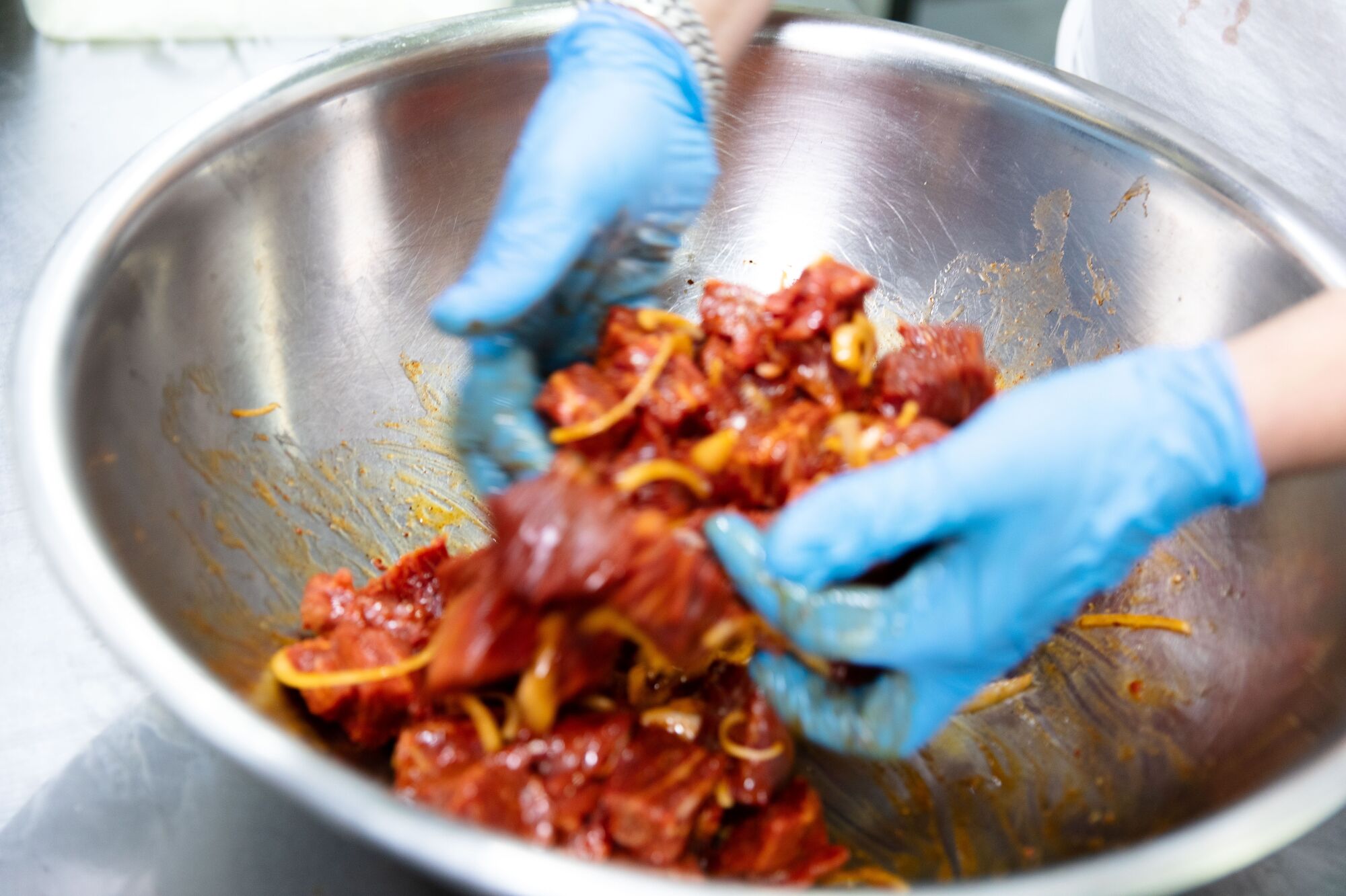 Mixing spices and onion with meat inside of Garni Meat Market store.