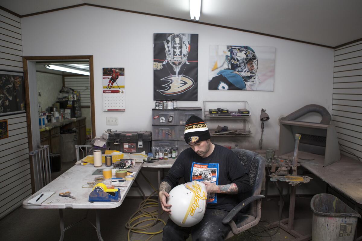 Noah Ennis, a helmet and hockey mask painter, works in his shop, Shell Shock Custom Paint in Fairbury, Neb.