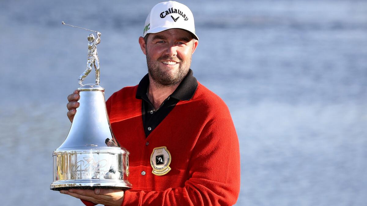Marc Leishman poses with the winner's trophy and the new ceremonial red sweater after winning the Arnold Palmer Invitational on Sunday.