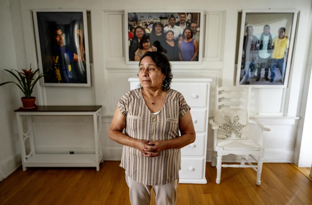 Dora Molina stands in front of large family photos including of her late husband, José Tomás Mejía.