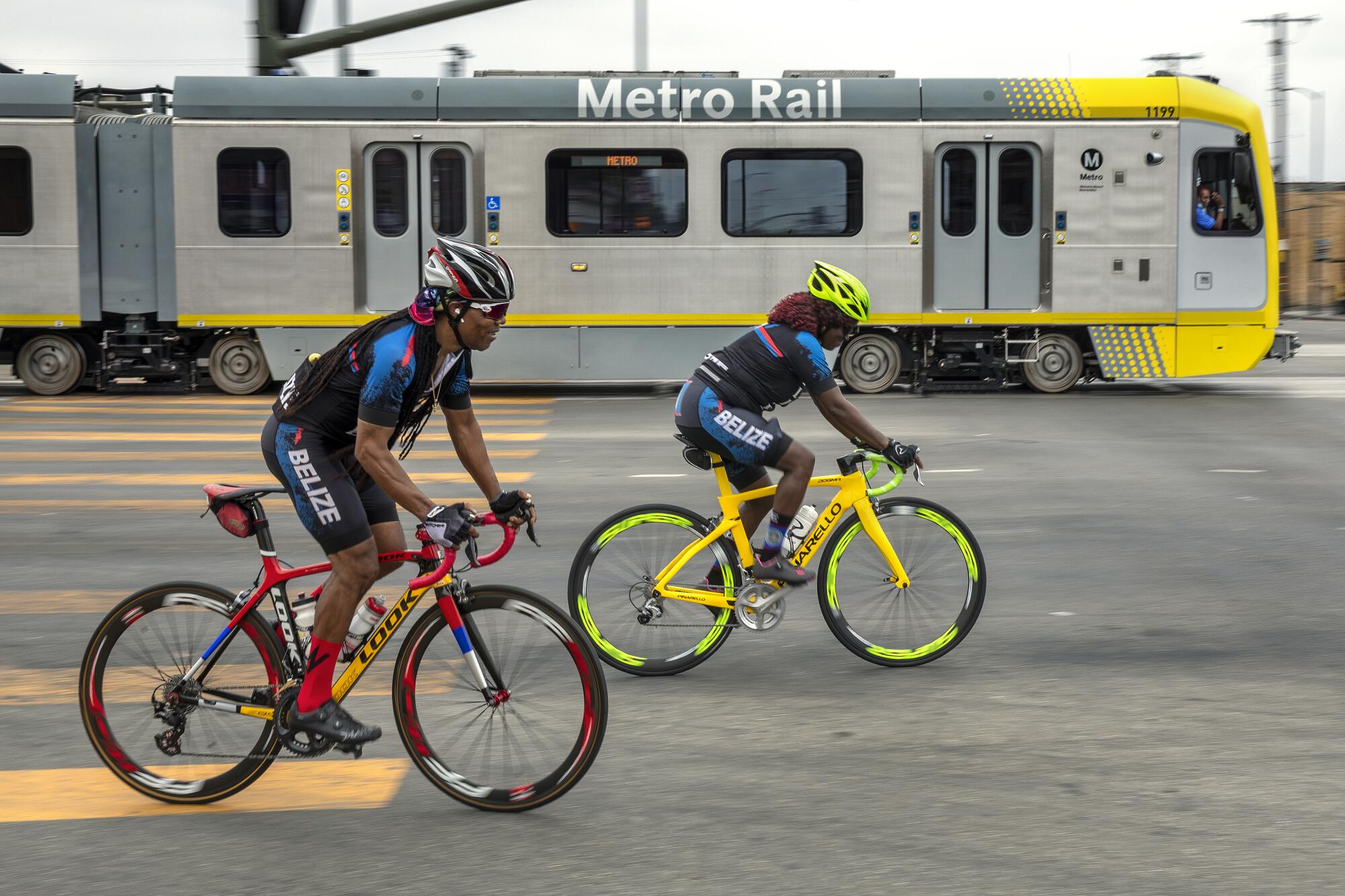 Bicyclists pedal beside a light rail car in Los Angeles