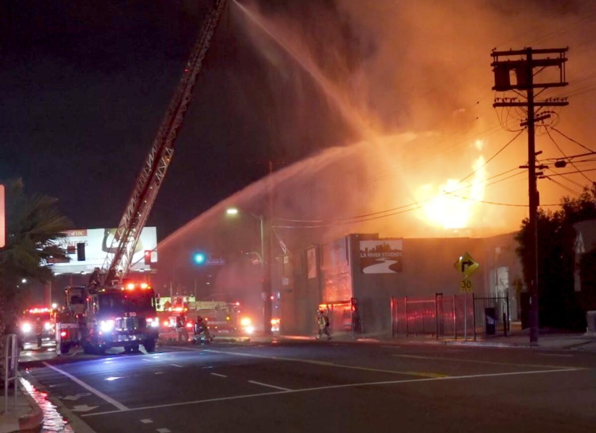 Crews fight a fire at a one-story commercial building at night.