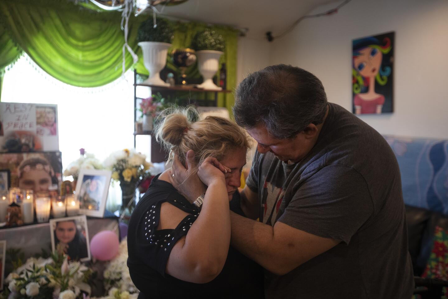 Lorena Pimentel de Salazar, 35, hugs her cousin Hans Bludau as they grieve in the living room, filled with flowers, candles and photographs.