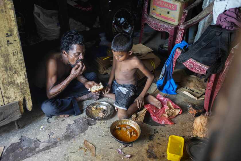 A father and son share a meal at their shanty in Colombo, Sri Lanka, Wednesday, Oct. 5, 2022. International creditors should provide debt relief to Sri Lanka to alleviate suffering as its people endure hunger, worsening poverty and shortages of basic supplies, Amnesty International said in a statement Wednesday. (AP Photo/Eranga Jayawardena)