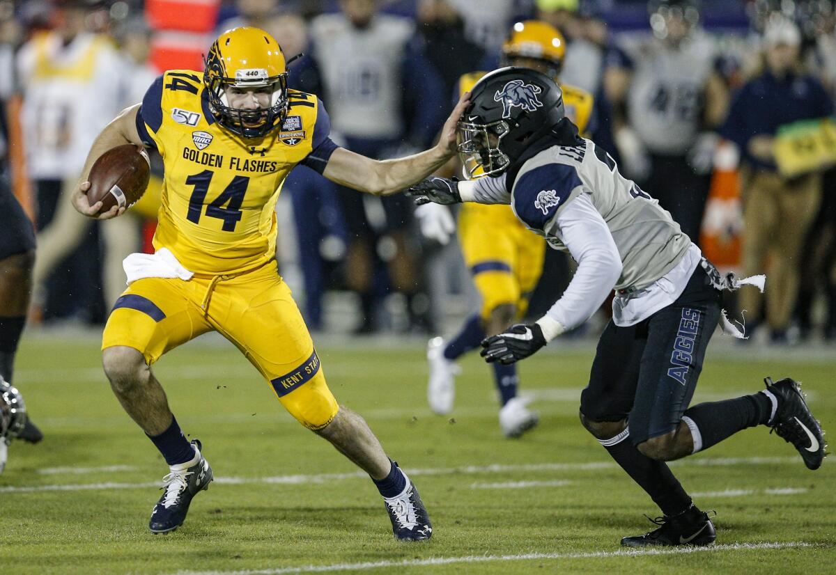 Kent State quarterback Dustin Crum carries the ball as Utah State safety Troy Lefeged Jr. defends in the Frisco Bowl.