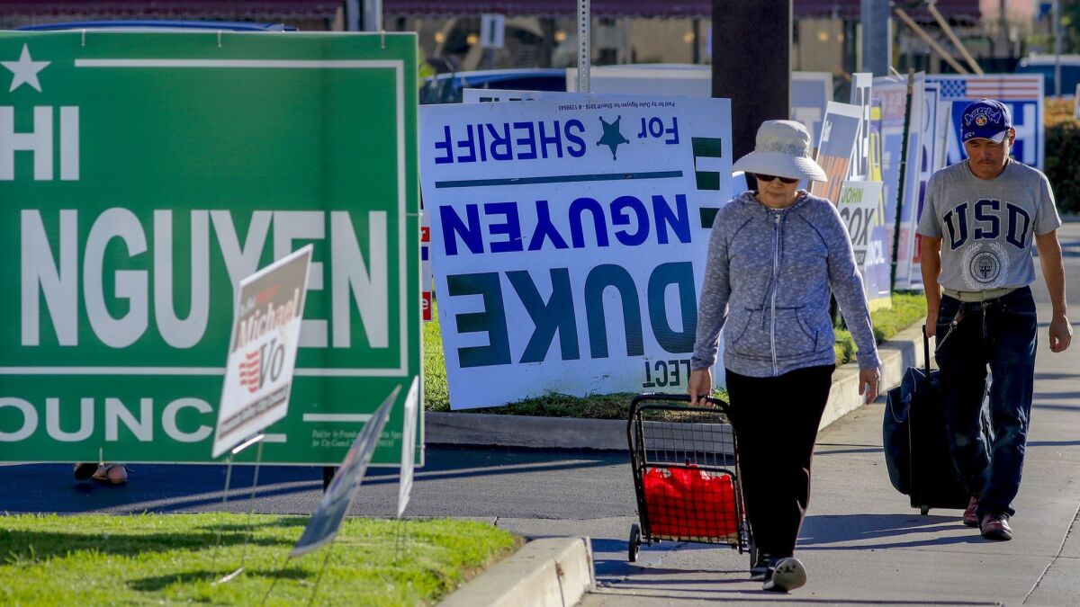 Pedestrians walk past a row of political signs and posters along Bolsa Avenue in Westminster. In Orange County, 24 people of Vietnamese descent ran for public office; 13 were poised to win.