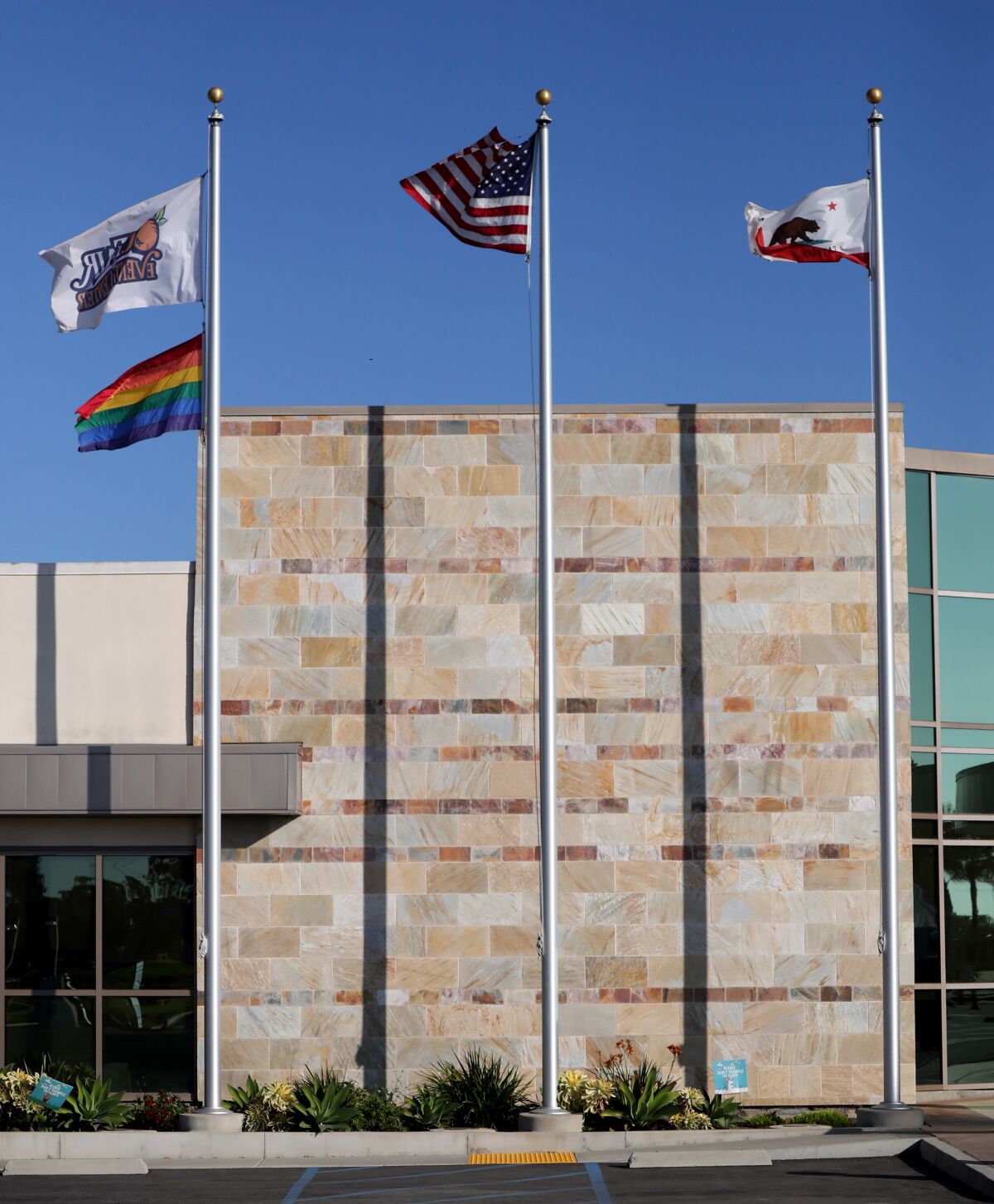 The OC Fair, LGBTQ, U.S. and California flags fly outside of the OC Fair & Event Center administration building.