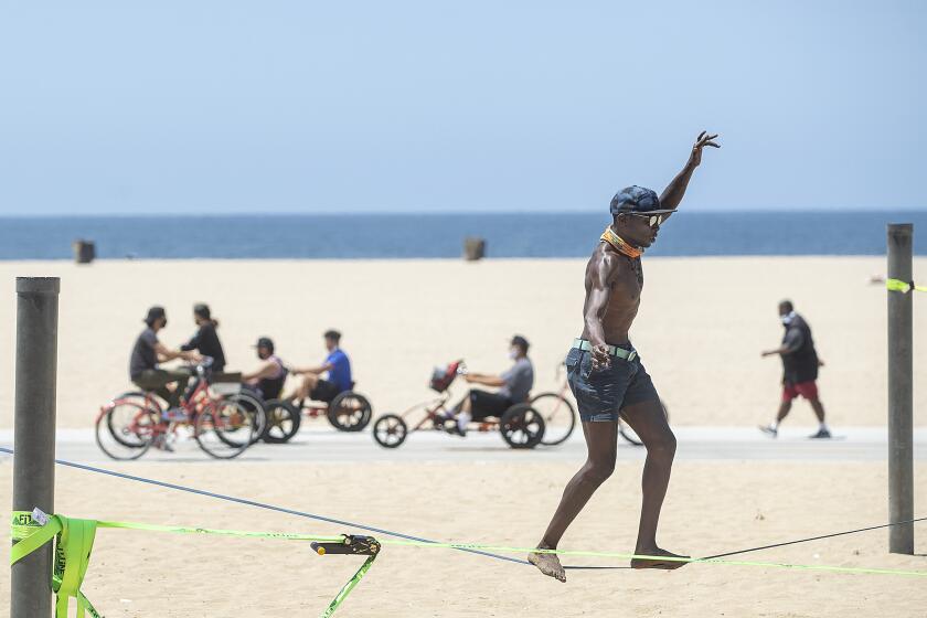 SANTA MONICA, CA - JUNE 29: Jacob Laiser, 38, of Venice, balances on a slack line, while working out at Santa Monica Beach on Monday, June 29, 2020 in Santa Monica, CA. L.A. County is expected to reach 100,000 cases of coronavirus.