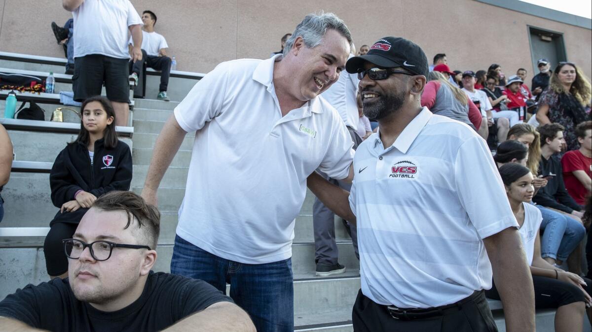 Former USC running backs coach Todd McNair chats with attorney Scott Carr before a game with the Village Christian Crusaders in Burbank on Friday.