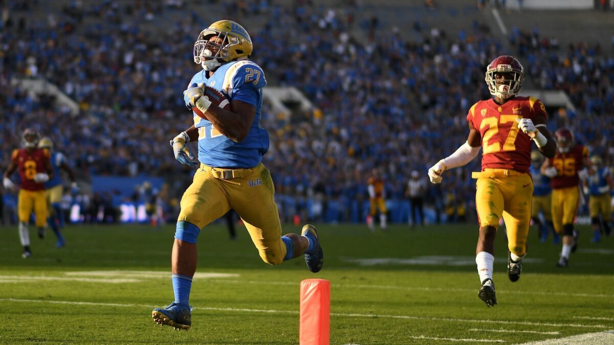 UCLA running Joshua Kelley scores a 55-yard touchdown in front of USC defensive back Ajene Harris in the 4th quarter at the Rose Bowl Saturday, Oct. 17, 2017.