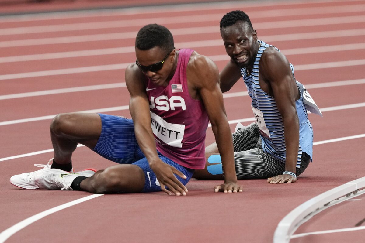 U.S. runner Isaiah Jewett and Nijel Amos of Botswana sit on the track.