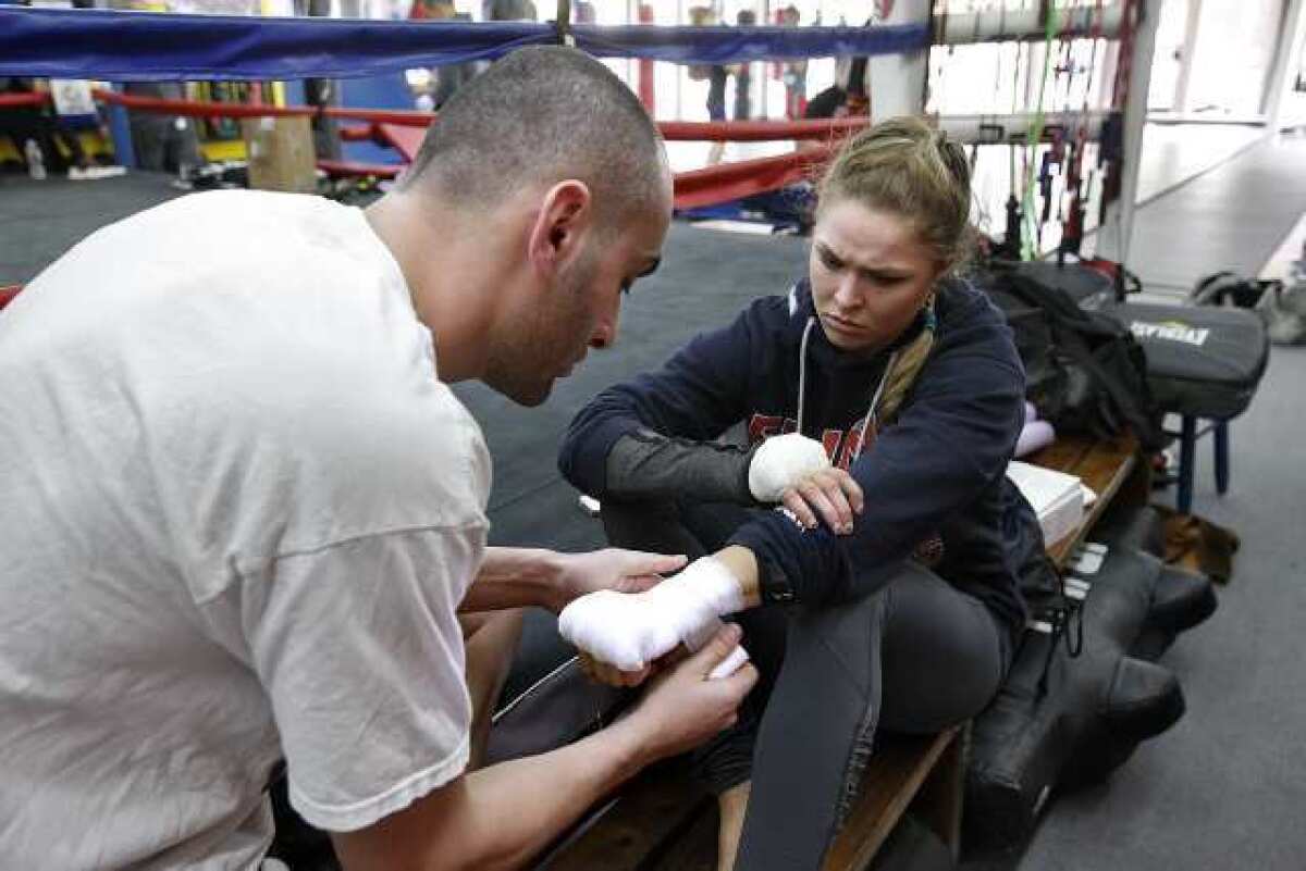UFC Champion Ronda Rousey gets her hands wrapped by her trainer Edmond Tarverdyan before a training session at the Glendale Fighting Club.