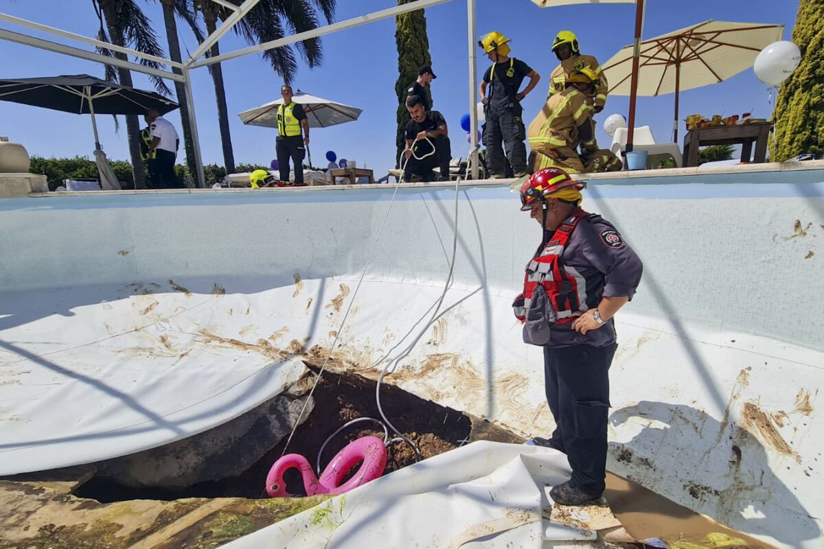 In this photo provided by Israel Fire and Rescue Services, Israeli firemen and rescuers work in a sinkhole formed in a swimming pool in Karmi Yosef, Israel, Thursday, July 21, 2022. Israeli police say they placed a couple under house arrest, a day after a man attending a party at their villa died after being sucked into a sinkhole that formed at the bottom of their swimming pool. The incident happened during a private party the couple hosted at their house in the town of Karmi Yosef, 40 kilometers (25 miles) southeast of Tel Aviv. (Israeli Fire and Rescue Services via AP)
