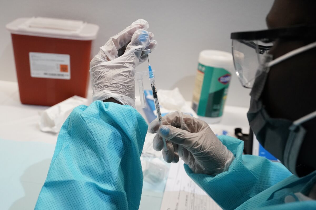 A health care worker fills a syringe with the Pfizer COVID-19 vaccine at the American Museum of Natural History in New York. 