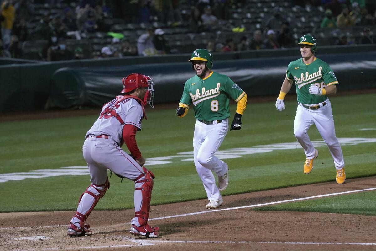 Oakland's Jed Lowrie (8) and Matt Chapman score past Angels catcher Drew Butera during the sixth inning.