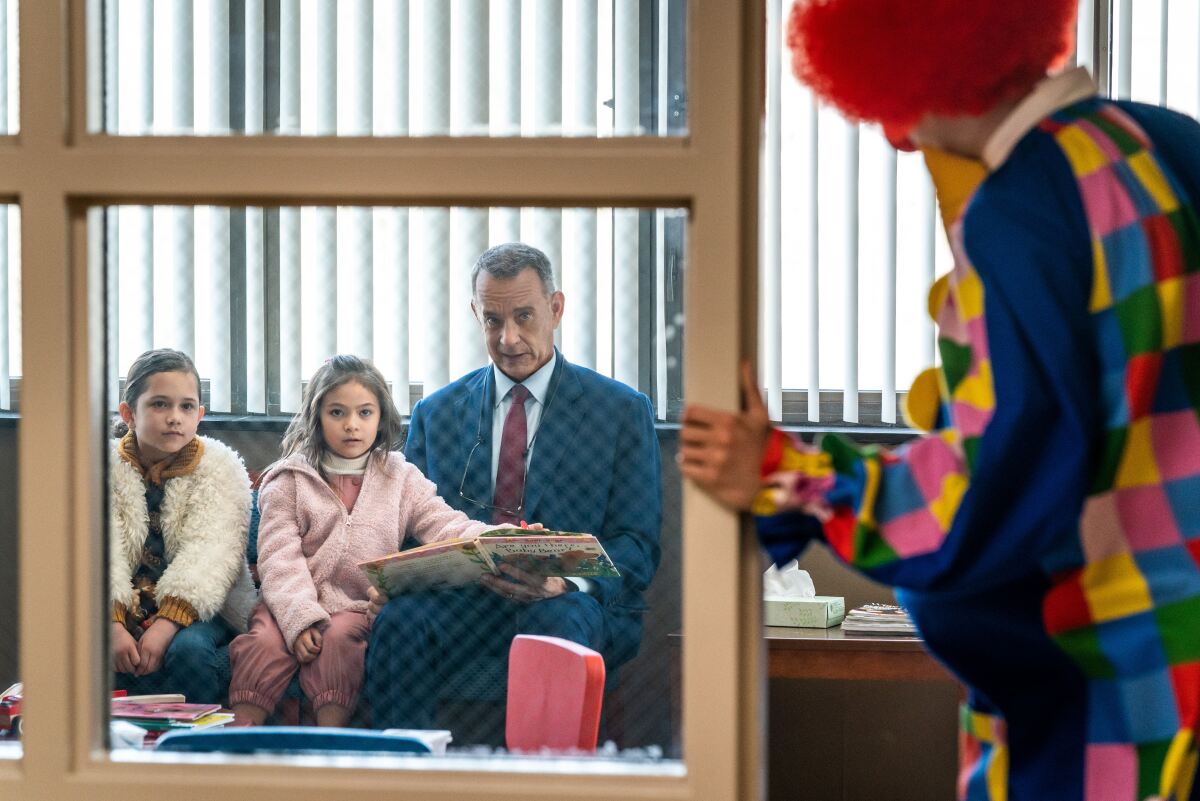 A man and two children look skeptically at a colorfully dressed clown.