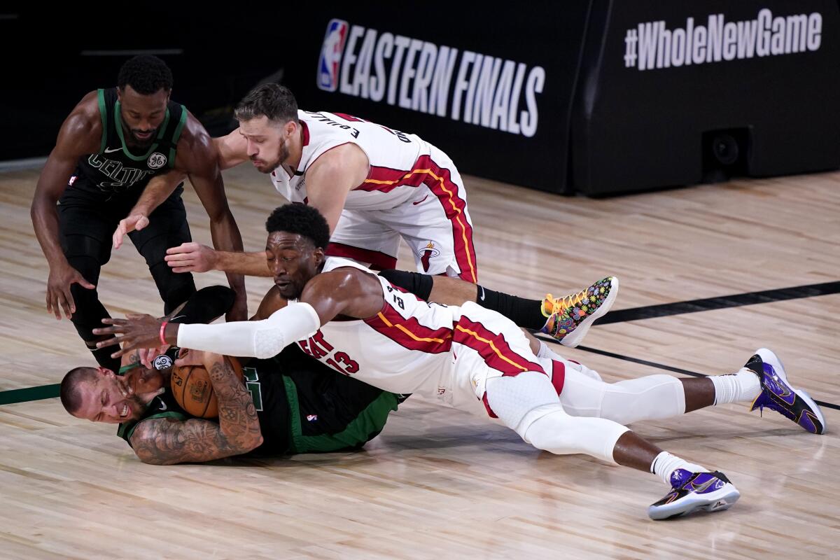 Boston's Kemba Walker and Daniel Theis attempt to gain control of a loose ball against Miami's Goran Dragic and Bam Adebayo.