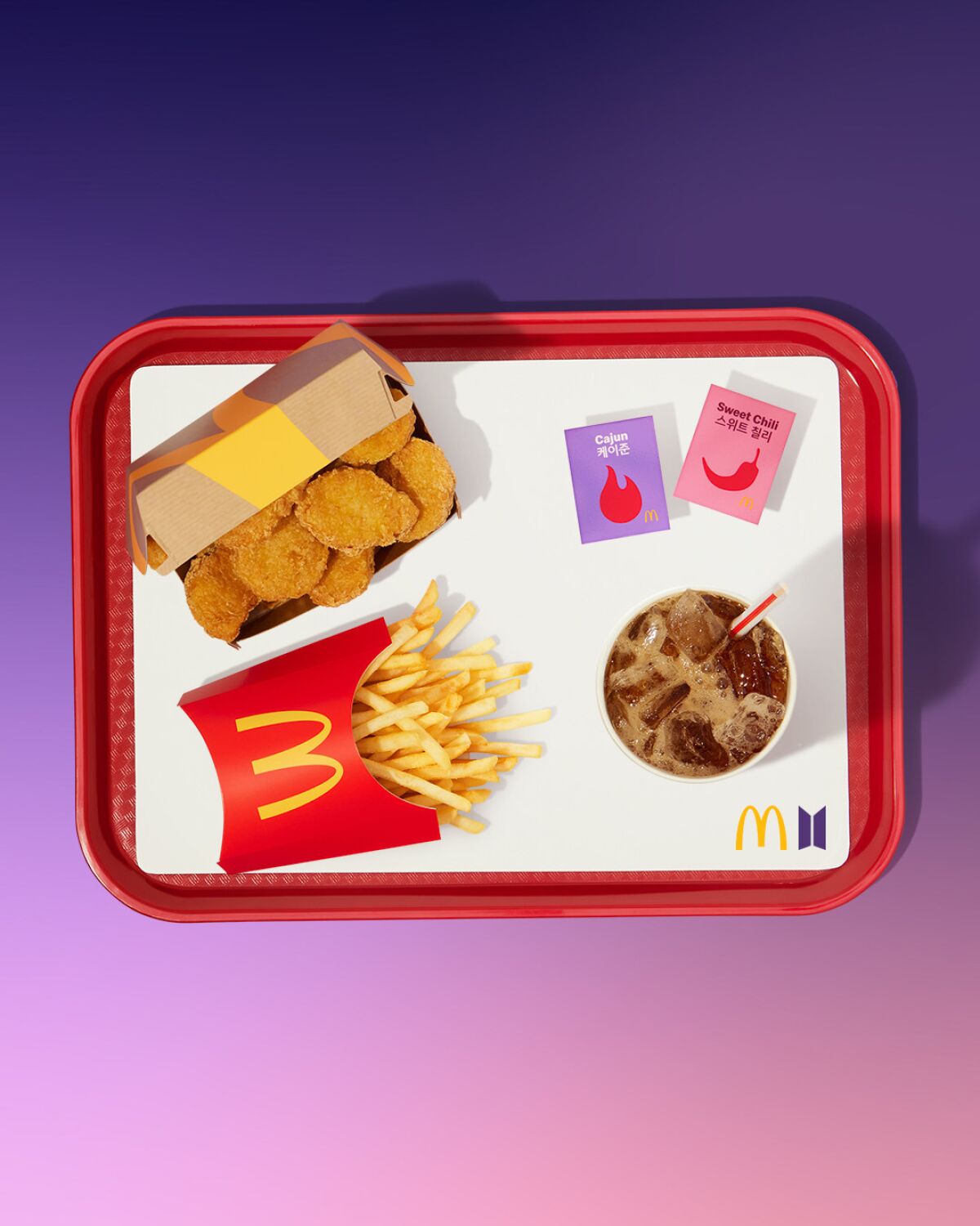 McNuggets, fries, a drink with a straw and two sauces on a paper-lined tray