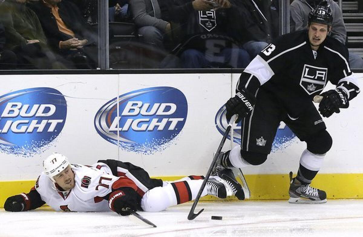 Kings winger Kyle Clifford comes up with the puck in a battle against Ottawa defenseman Joe Corvo during a game last month at Staples Center.