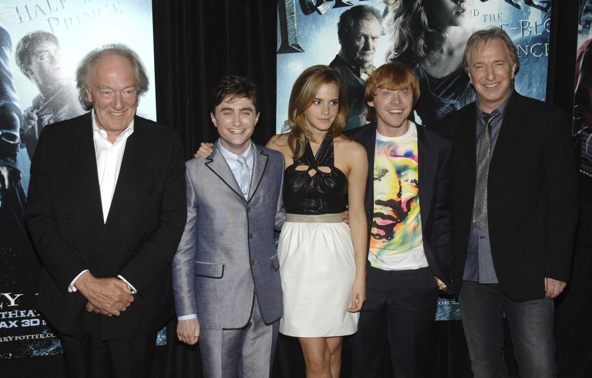 Michael Gambon wears a black suit while posing for pics next to Daniel Radcliffe, Emma Watson, Rupert Grint and Alan Rickman