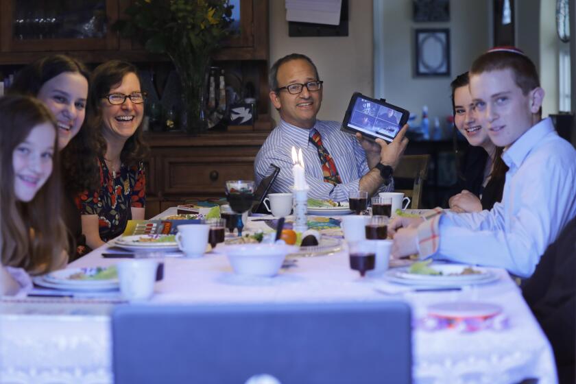 Rabbi Scott Meltzer of Ohr Shalom Synagogue, center, hosted seder with his family at his University City home which was live streamed via Zoom to the congregation and others on April 8, 2020. From left are his daughters Yael, Maital, wife Jennifer, daughter Shayna, and son Nadiv. Meltzer, shown here showing the congregation on the webcast his set up, used a computer and two tablets to stream the service.