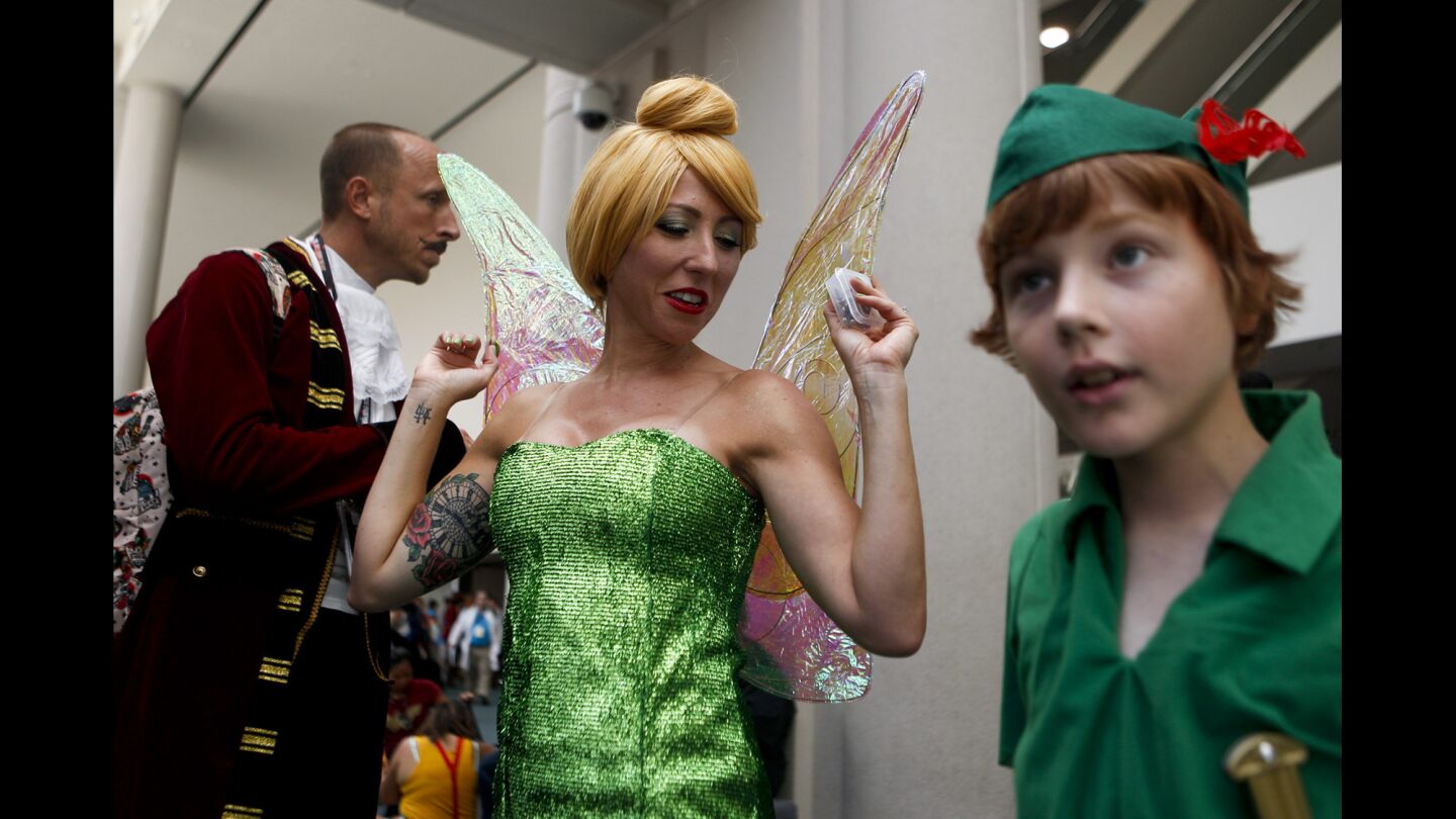 Meagan Topmiller, center, of Temecula fixes her wings before exploring the San Diego Convention Center with her husband, James, left, and Hadyn Topmiller, during the first day of the Comic-Con International convention at the San Diego Convention Center.