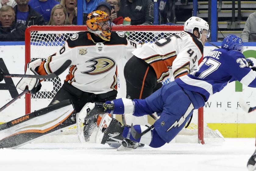 Anaheim Ducks defenseman Andy Welinski (45) sends Tampa Bay Lightning center Yanni Gourde (37) flying after a check in front of goaltender Ryan Miller (30) during the first period of an NHL hockey game Tuesday, Nov. 27, 2018, in Tampa, Fla. (AP Photo/Chris O'Meara)