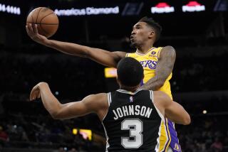 Los Angeles Lakers guard Malik Monk, top, drives to the basket against San Antonio Spurs forward Keldon Johnson (3) during the first half of an NBA basketball game, Monday, March 7, 2022, in San Antonio. (AP Photo/Eric Gay)