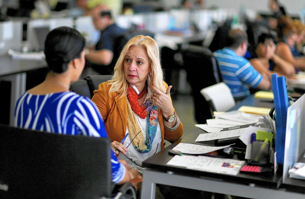 Insurance advisor Maria Elena Santa Coloma, right, helps a client in Miami sign up for a health plan under the Affordable Care Act.