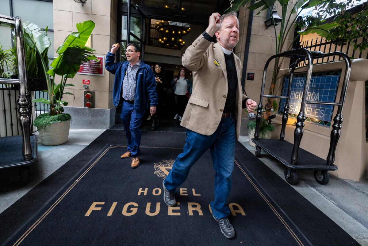 Men walking out of the Hotel Figueroa with their fists in the air.
