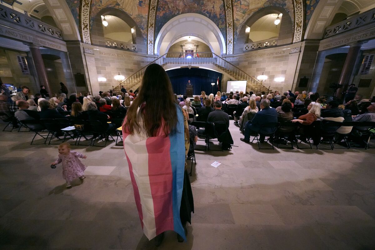 Glenda Starke wears a transgender flag as a counterprotest during a rally in favor of a ban on gender-affirming health care legislation, Monday, March 20, 2023, at the Missouri Statehouse in Jefferson City, Mo. (AP Photo/Charlie Riedel)