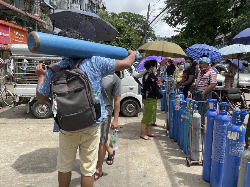 A man carries an oxygen tank while others line up with their oxygen tanks outside an oxygen refill station in Pazundaung township in Yangon, Myanmar, Sunday, July 11, 2021. Myanmar is facing a rapid rise in COVID-19 patients and a shortage of oxygen supplies just as the country is consumed by a bitter and violent political struggle since the military seized power in February. (AP Photo)