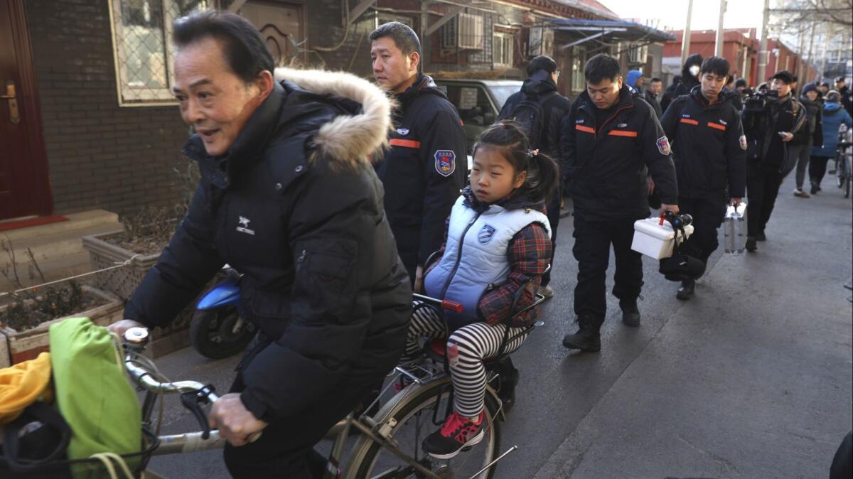 A man rides with a student past crime scene investigators Jan. 8 as they leave the Beijing No. 1 Affiliated Elementary School of Xuanwu Normal School.