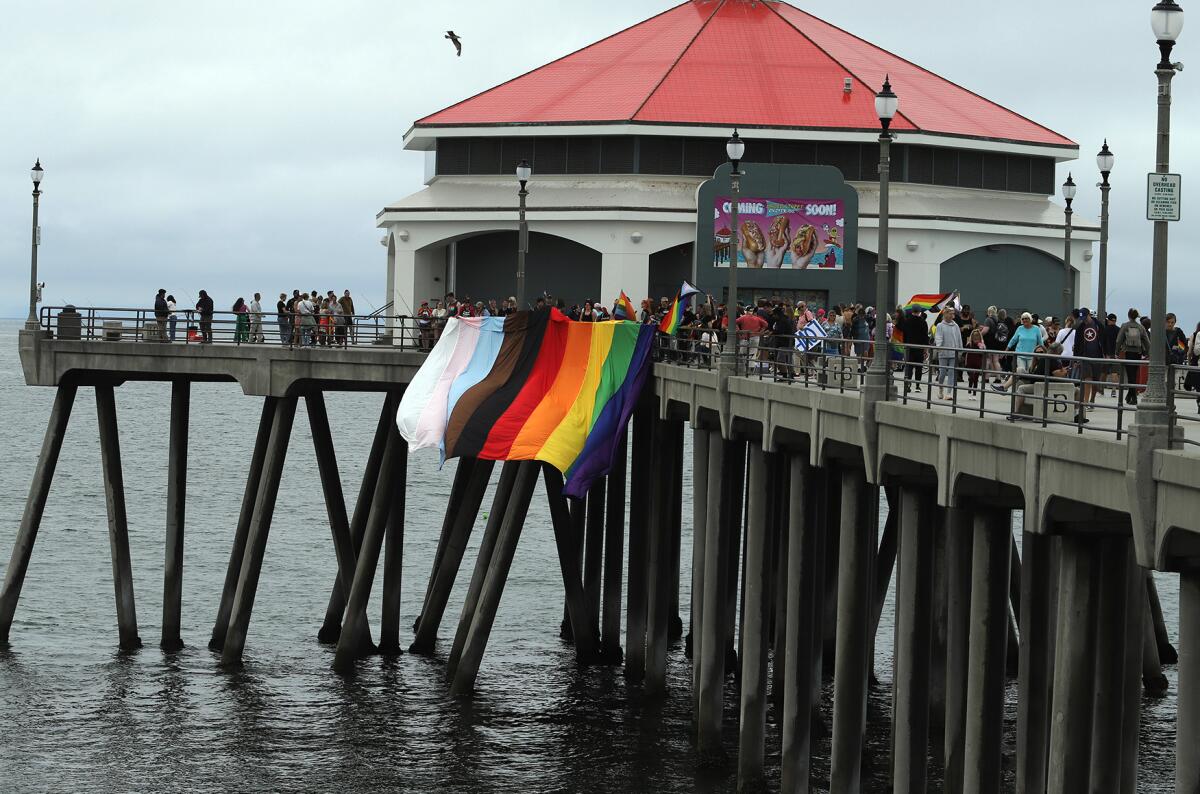  LGBTQ+ supporters cheer as a giant rainbow Pride flag hangs from Huntington Beach Pier on May 21.