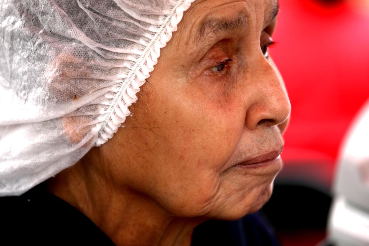 A woman wearing a hair net takes a break from walking a picket line. 