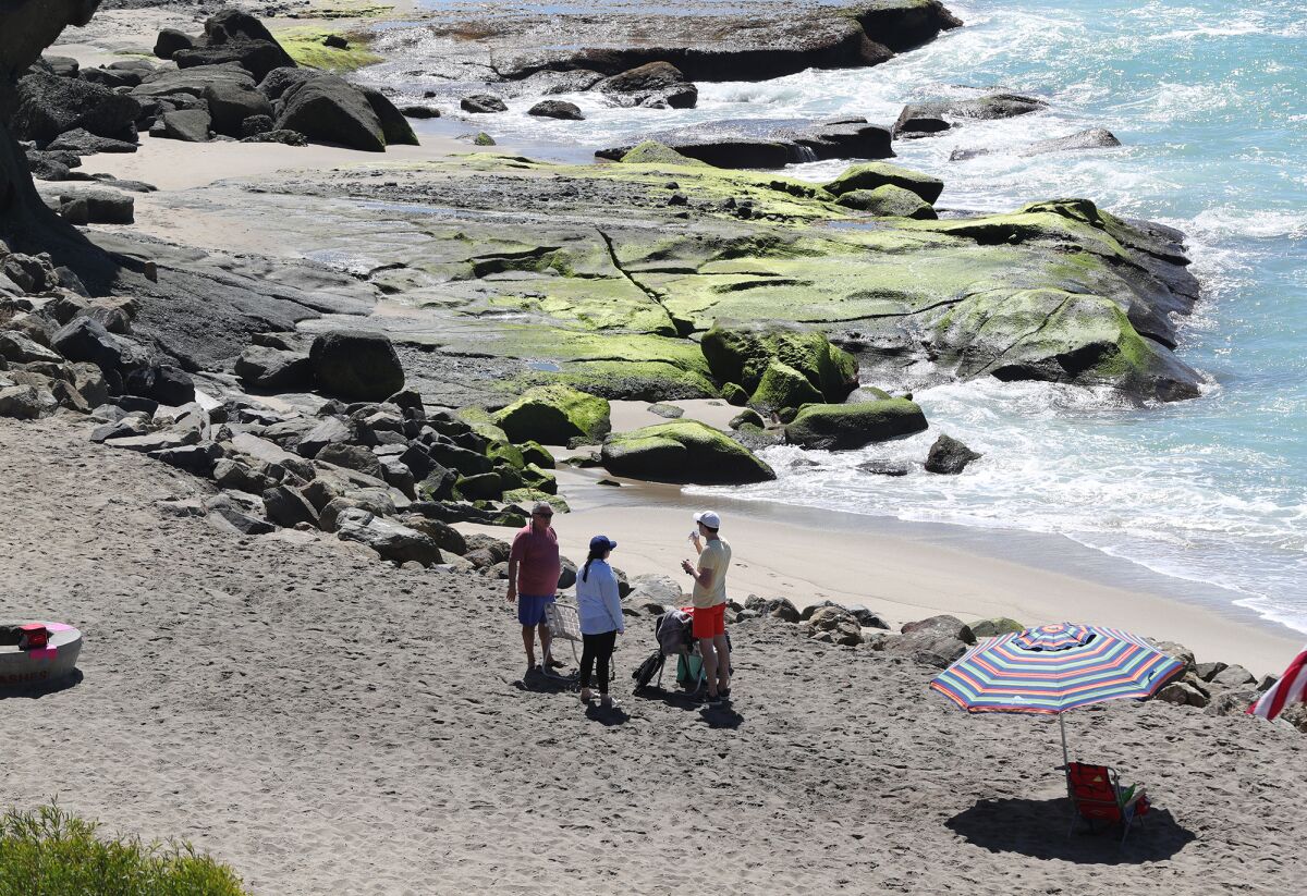 Beachgoers have a chat on the sand at Aliso Beach in South Laguna on Thursday.