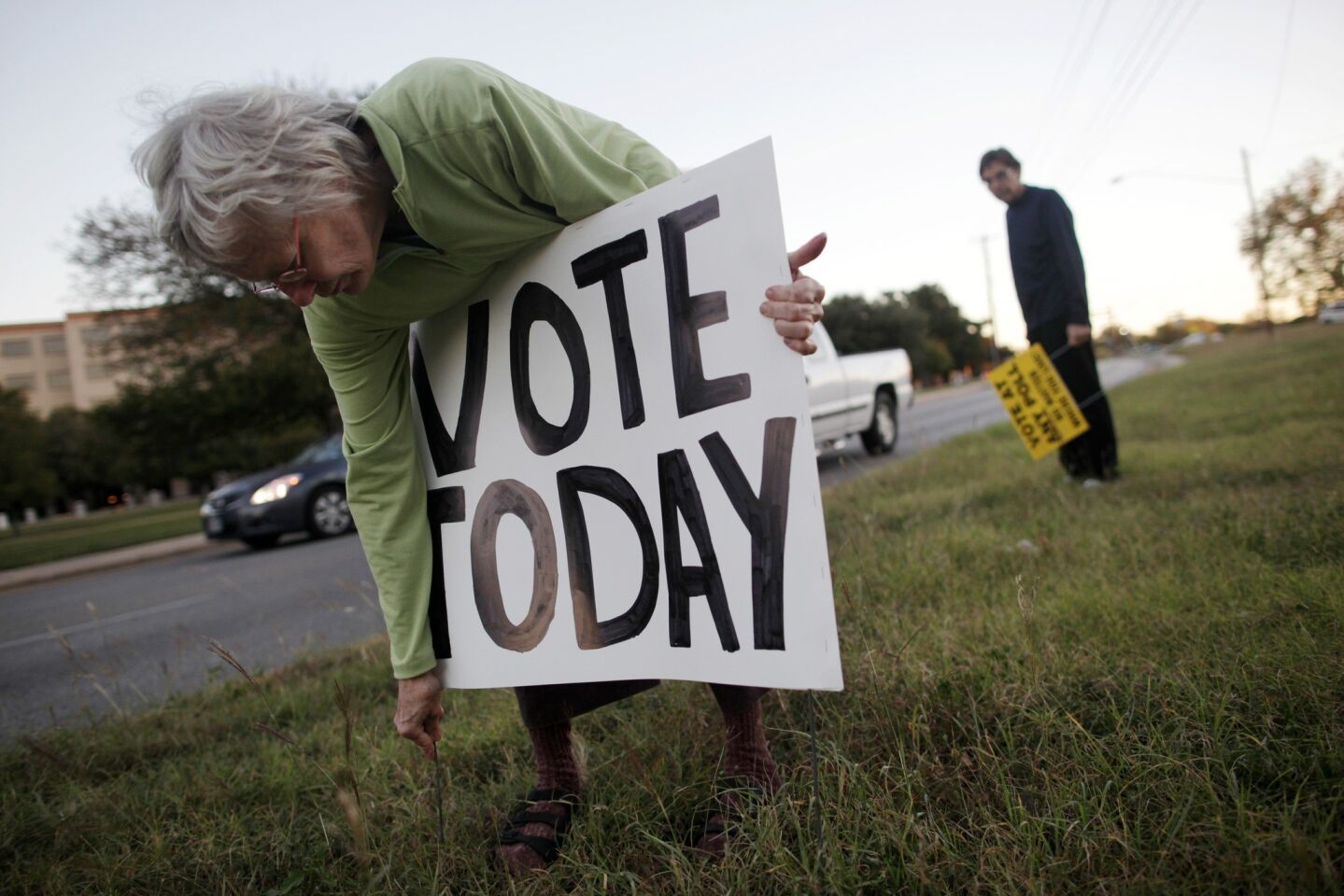 Carol, left, and Amon Burton place signs on Lamar Boulevard before polls open in Austin, Texas.