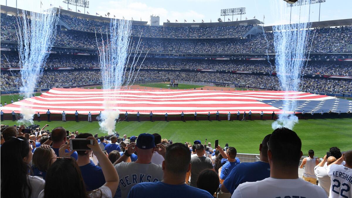 Fans stand for the national anthem during Opening Day at Dodger Stadium.