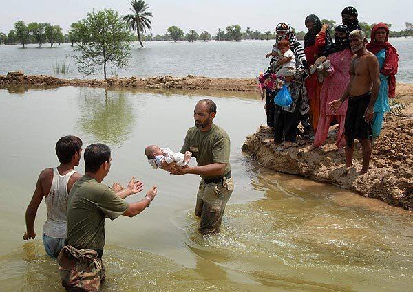 Pakistan army soldiers pass a baby across a watercourse as they help people flee their flooded village. The death toll from massive floods in northwestern Pakistan rose to 1,100 on Sunday as rescue workers struggled to save more than 27,000 people.