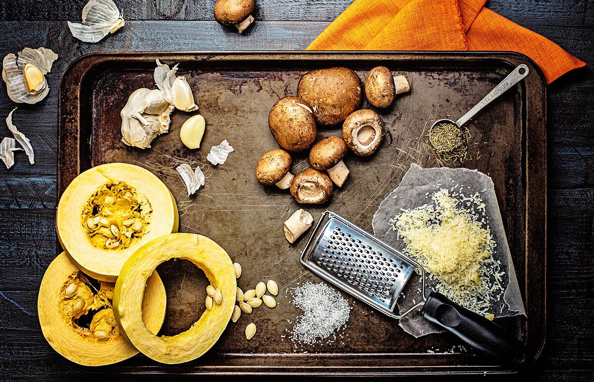 Ingredienti per gli spaghetti di zucca con olio d'oliva, aglio e funghi arrostiti su una teglia.