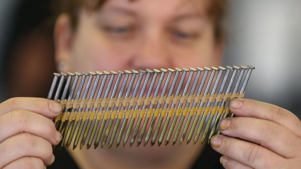 Diane Brogdon, a machine operator at the Mid Continent Nail Corp., looks at a set of nails that fit into a nail gun at the company production factory in Poplar Bluff, Mo.