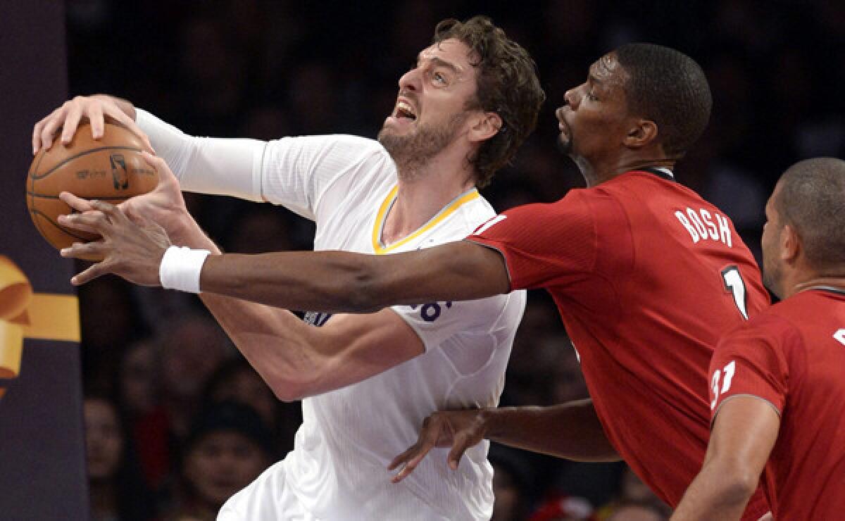 Lakers center Pau Gasol, left, tries to put up a shot in front of Miami Heat center Chris Bosh during the Lakers' Christmas Day loss. Gasol hopes to be healthy enough to play Tuesday against the Milwaukee Bucks.