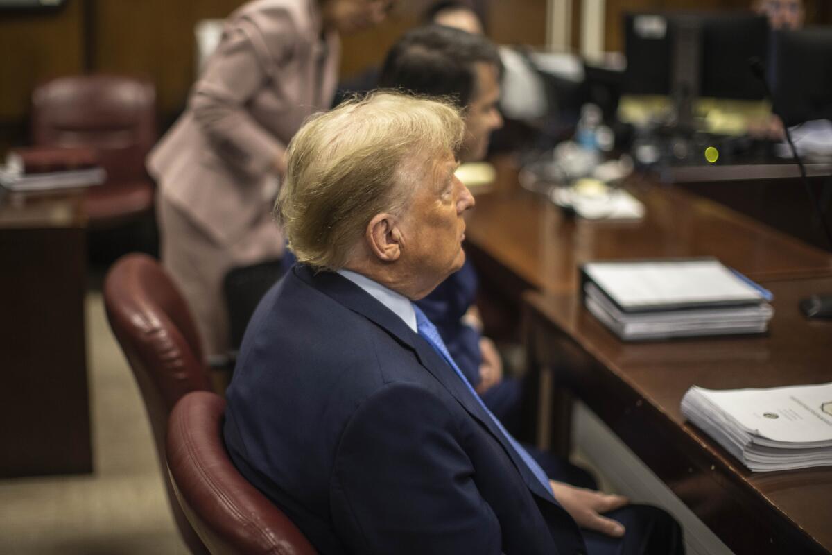 A profile view of Donald Trump sitting at the defense table in court.