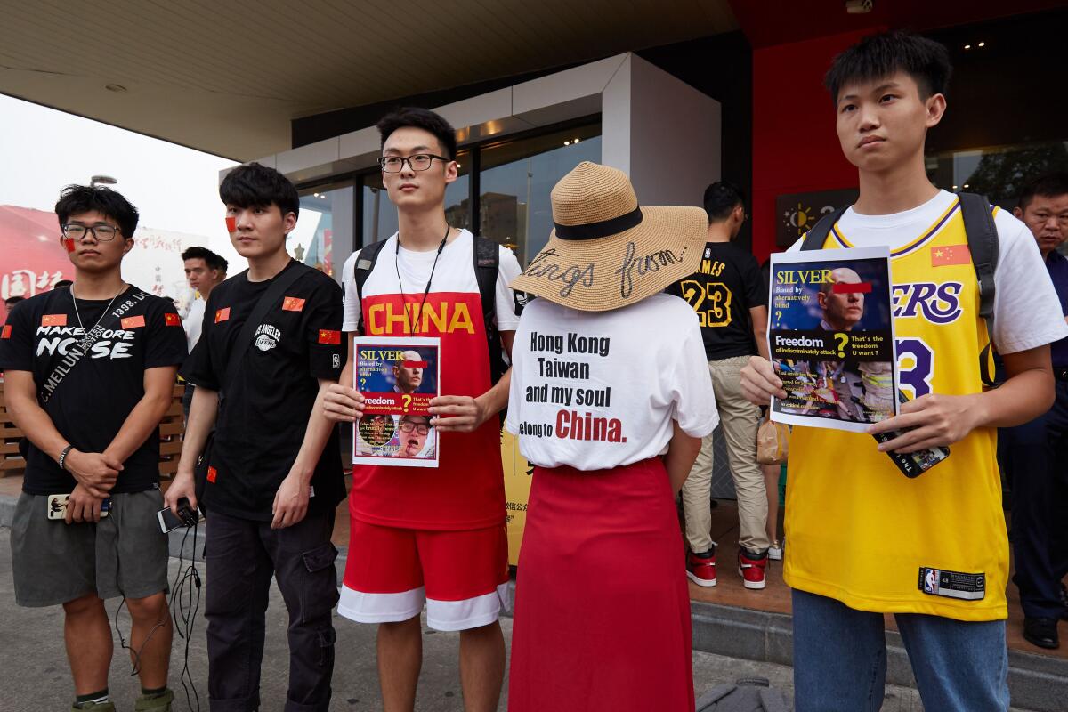 Basketball fans hold posters referencing comments made by NBA Commissioner Adam Silver.